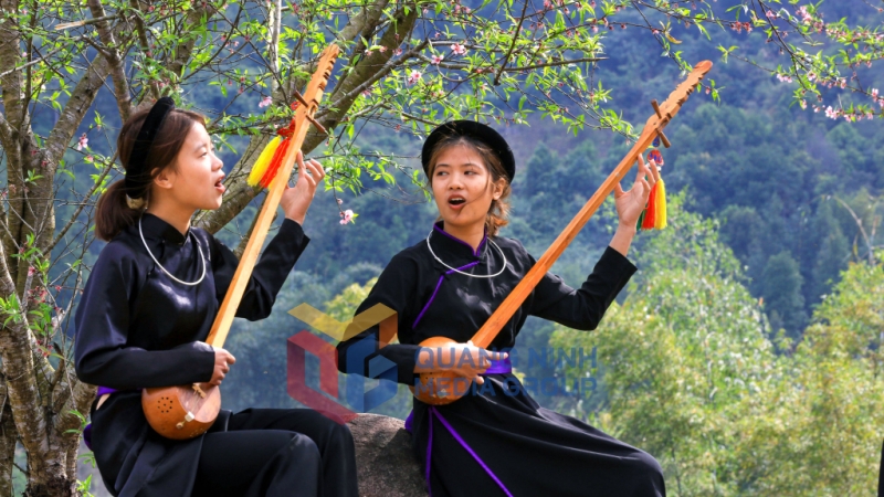 Thiếu nữ dân tộc Tày hát then và chơi đàn tính dưới gốc hoa đào ở bản Khe O, xã Lục Hồn (2-2025). Ảnh: Phạm Học