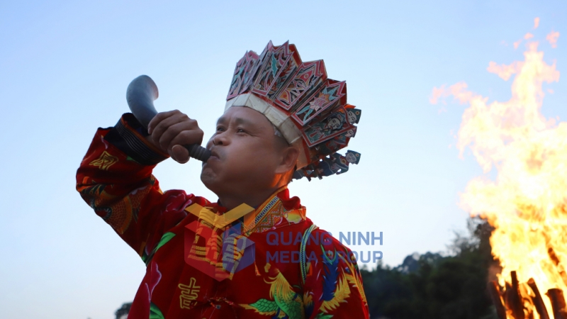 Một thầy cúng người Dao sử dụng tù và làm nhạc cụ tạo giai điệu cho nghi lễ nhảy lửa. Ảnh: Phạm Học