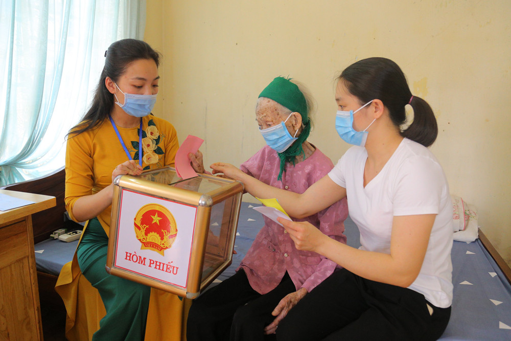 Cử tri Lẩu Tài Chể (106 tuổi), khu 4, phường Hồng Gai, TP Hạ Long, tuy không đi lại được, nhưng vẫn minh mẫn, được cán bộ phường trợ giúp đã tự tay bỏ phiếu bầu của mình. Ảnh: Minh Hà