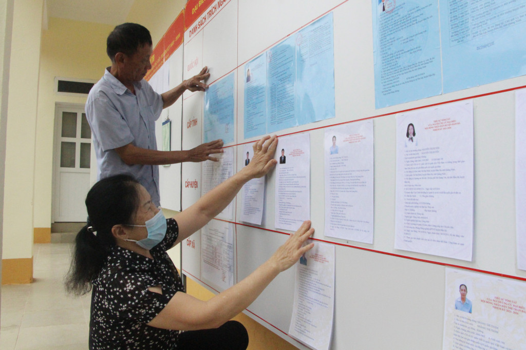 Bà Đặng Thị Long, Tổ trưởng Tổ bầu cử số 4 thị trấn Đầm Hà (huyện Đầm Hà) cùng thành viên tổ bầu cử niêm yết danh sách người ứng cử (tháng 4/2021).