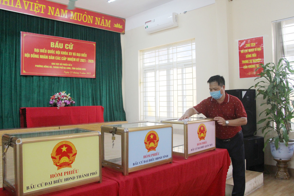Thành viên Tổ bầu cử khu vực bỏ phiếu số 5 phường Hồng Hà (TP Hạ Long) khử khuẩn đồ vật bên trong phòng bỏ phiếu đảm bảo công tác phòng dịch (ngày 22/5/2021).