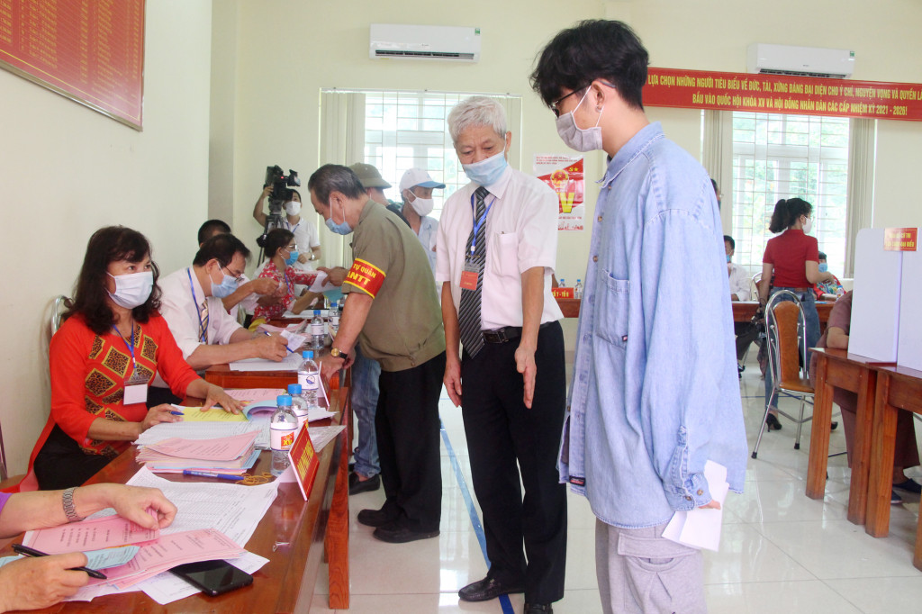 Ông Phạm Văn Kính, Tổ trưởng Tổ bầu cử khu vực bỏ phiếu số 6 phường Hồng Hà (TP Hạ Long) hướng dẫn cử tri giữ khoảng cách an toàn trong ngày bầu cử.