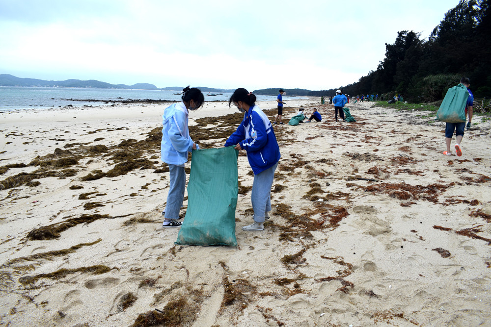 Khách du lịch cùng người dân Cô Tô tham gia dọn rác tại bãi biển Hồng Hải (xã Đồng Tiến) đầu tháng 4/2021