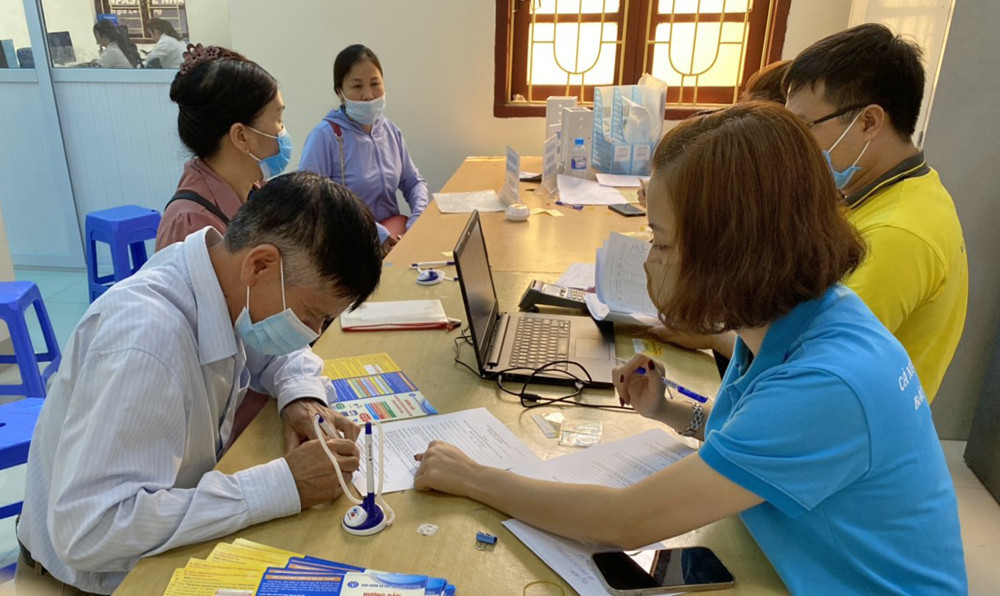 Cán bộ Bảo hiểm xã hội huyện Tiên Yên hướng dẫn người dân tham gia BHXH. Ảnh Thu Nguyệt.