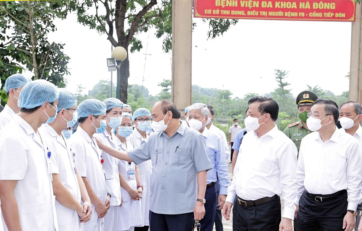 Chủ tịch nước Nguyễn Xuân Phúc thăm hỏi các nhân viên y tế làm việc cơ sở thu dung, điều trị bệnh nhân COVD-19 của Bệnh viện Đa khoa Hà Đông tại phường Hoàng Liệt, quận Hoàng Mai. (Ảnh: Thống Nhất/TTXVN)