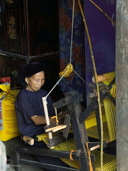 Nong Thi Phuong, 81, uses a loom to weave fabric.