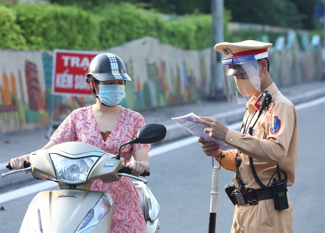 A police officer checks travel passes and related documents of a woman at the checkpoint near Chương Dương Bridge, Hà Nội, on September 4.