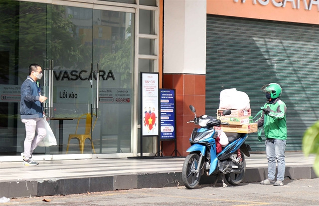 A man receives an order from a Grab delivery shipper in HCM City on July 7, 2021.