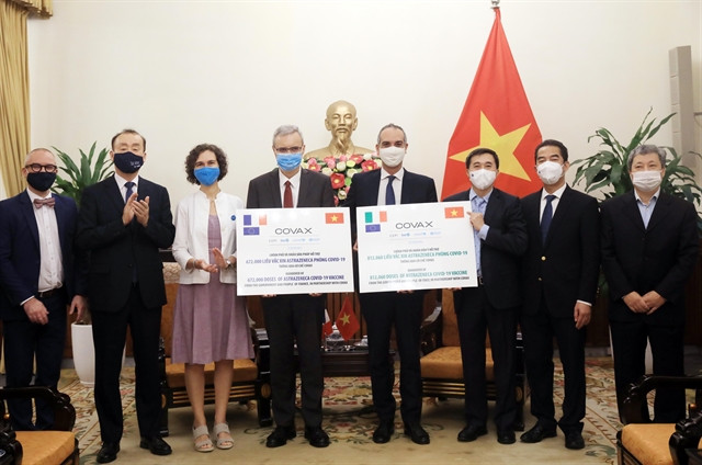 From second left: Kidong Park, Representative of the World Health Organisation (WHO) in Việt Nam; Lesley Miller, Deputy Representative of UNICEF in Việt Nam; Nicolas Warnery, French ambassador to Việt Nam; Paolo Epifani, Charge d’Affaires Italian Embassy in Việt Nam; Vietnamese deputy health minister Trần Văn Thuấn; and Vietnamese deputy foreign minister Tô Anh Dũng participate in the symbolic handover ceremony of vaccine donation held in Hà Nội on Tuesday. 