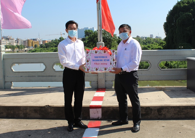 Đồng chí Đỗ Văn Tuấn, Ủy viên Ban thường vụ Thành ủy, Phó Chủ tịch UBND Thành phố Móng Cái (Việt Nam) (bên phải)  tặng quà chúc mừng quốc khánh Trung Quốc.
