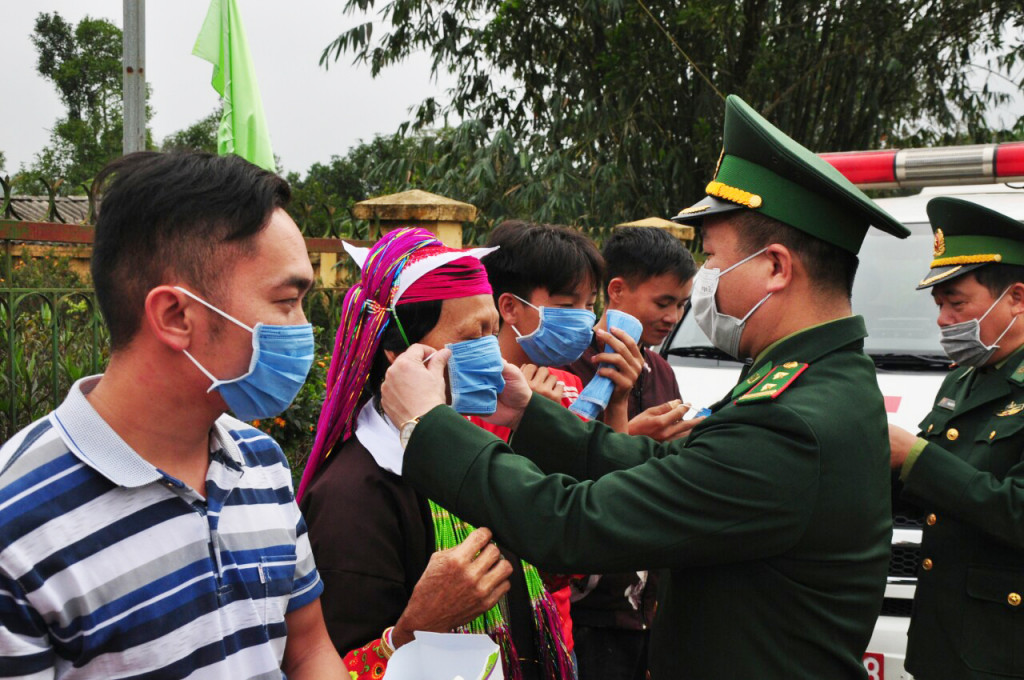 Cán bộ, chiến sĩ Đồn Biên phòng Cửa khẩu Hoành Mô, huyện Bình Liêu hướng dẫn đồng bào đeo khẩu trang đúng cách để phòng dịch COVID-19_Ảnh: baoquangninh.com.vn