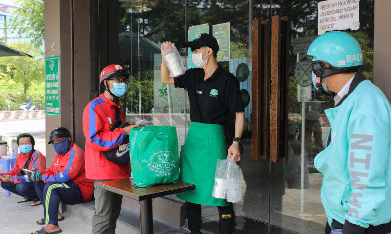Shippers wait to pick up orders at a coffee shop in Ho Chi Minh City on September 16, 2021. Photo by VnExpress/Quynh Tran