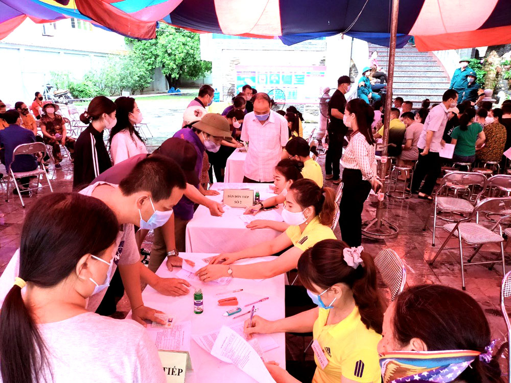 Chị em Hội LHPN phường Cẩm Sơn (áo vàng bên phải) giúp người dân trên địa bàn kê khai tiêm phòng Covid-19 mũi 2