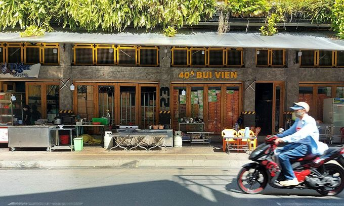 A man drives past a restaurant with tables placed outside on Bui Vien Street in HCMC's District 1, Oct. 28, 2021. 
