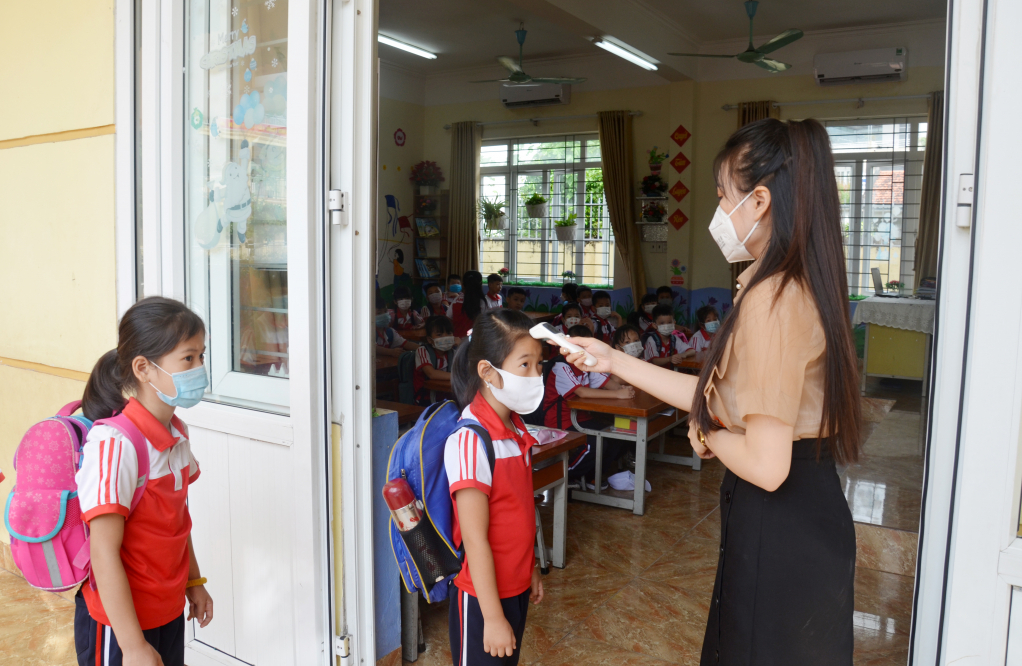 Học sinh đo thân nhiệt khi đến trường. Ảnh chụp tại Trường TH Cẩm Bình, TP Cẩm Phả. Ảnh: Lan Anh