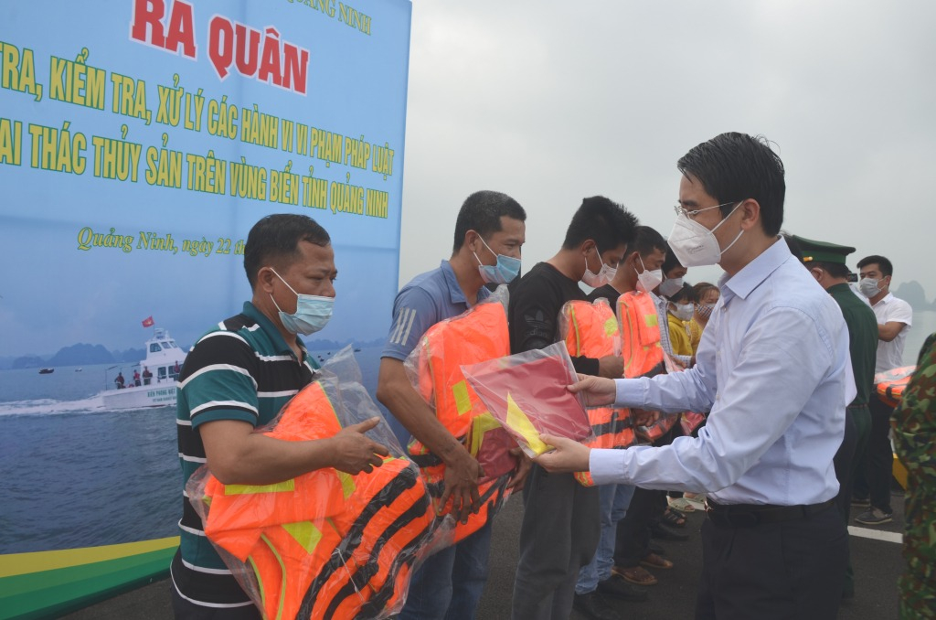 Đồng chí Phạm Văn Thành, Phó Chủ tịch UBDN tỉnh trao tặng cờ Tổ quốc, áo phao và phao cứu sinh cho ngư dân. 