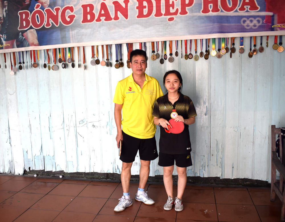 Anh Nguyên Xuân Điệp và con gái Nguyễn Hà Vi bên những tấm huy chương mà họ giành được qua các kỳ thi đấu thể thao