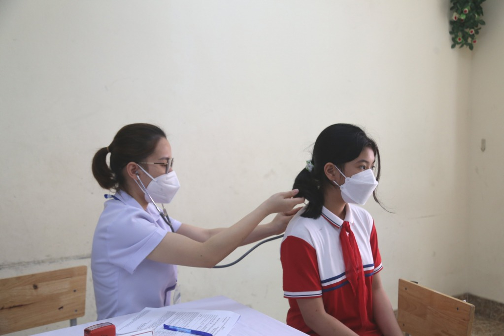 Cán bộ y tế khám sàng lọc cho học sinh trước khi tiêm.