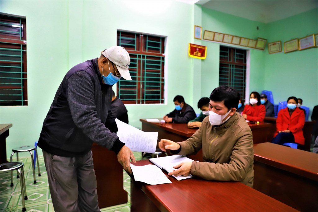 Cán bộ thôn Ngàn Vàng Dưới, xã Đồng Tâm (huyện Bình Liêu) phát phiếu lấy ý kiến về việc sáp nhập thôn năm 2022.
