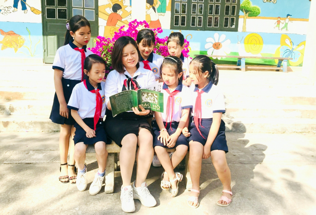 Hay là : Các em học sinh lắng nghe các câu chuyện về tấm gương đạo đức Hồ Chí Minh do cô Hợi kể.