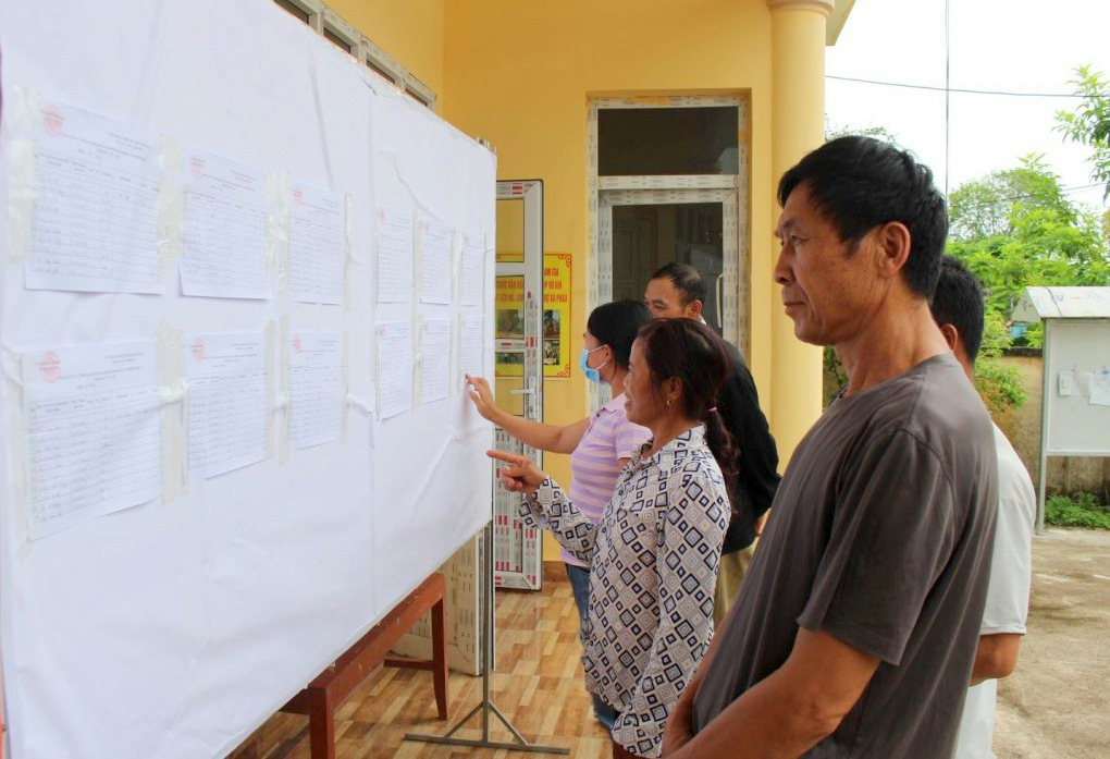 Người dân xã Quảng An (huyện Đầm Hà) theo dõi danh sách cử tri được niêm yết công khai tại điểm bầu cử được đăt tại các nhà văn hóa thôn