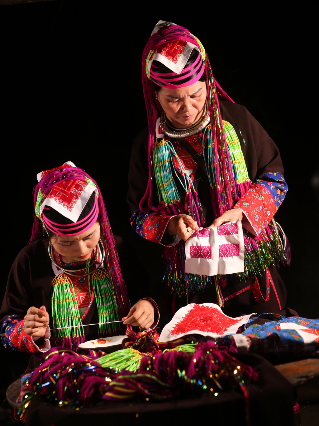 Ảnh 3: Chị Phùn Thị Tâm đang cùng mẹ thêu khăn áo và làm những dải rua trên trang phục dân tộc Dao Thanh Y.