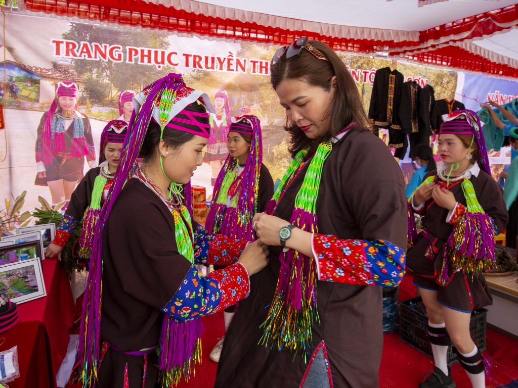 Ảnh 7: Phùn Thị Tâm đang giới thiệu trang phục Dao Thanh Y cho du khách trong hội chợ.