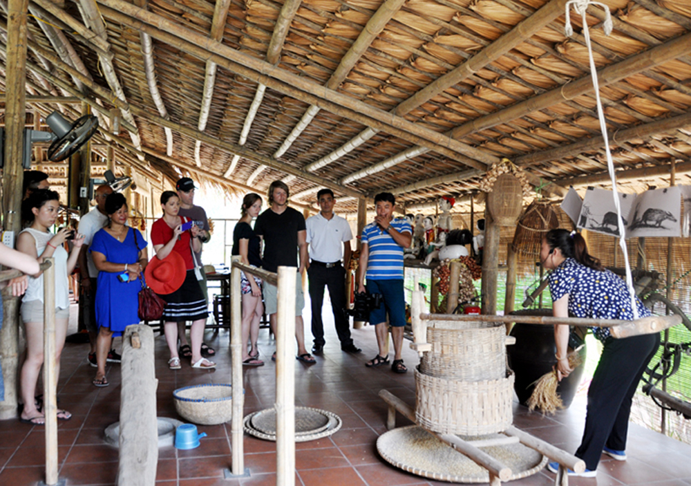 Du khách trải nghiệm xay lúa ở Khu du lịch làng quê Yên Đức.