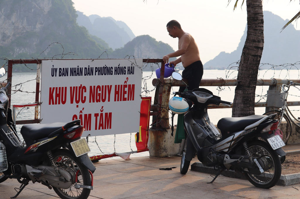 Mặc dù đã có biển cấm tắm nhưng vẫn đông người trèo qua hàng rào để xuống tắm. 