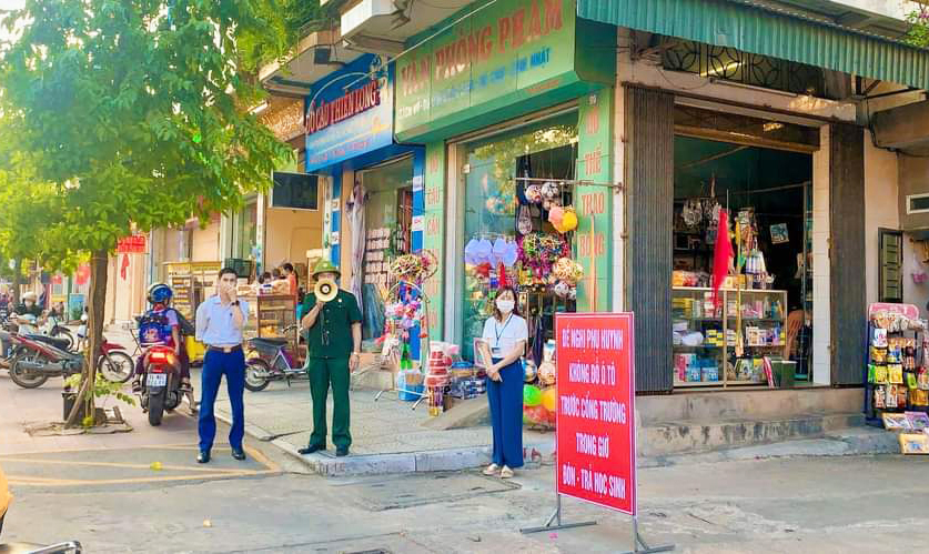 Tổ CCB phường Quang Trung cùng giáo viên trong Trường tiểu học Quang Trung dùng loa để nhắc nhỏ, phân luồng, đảm bảo giao thông tại giờ tan lớp của học sinh.