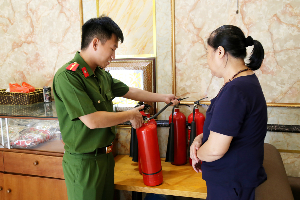 Cán bộ PCCC lồng ghép hướng dẫn chủ cơ sở karaoke cách sử dụng bình chữa cháy đúng cách, trong khi kiểm tra.