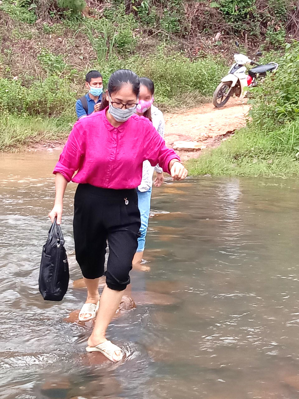 Các thầy cô dò dẫm từng bước chân qua suối thôn Pắc Cương, xã Hoành Mô trong một buổi đi vận động học sinh trở lại trường