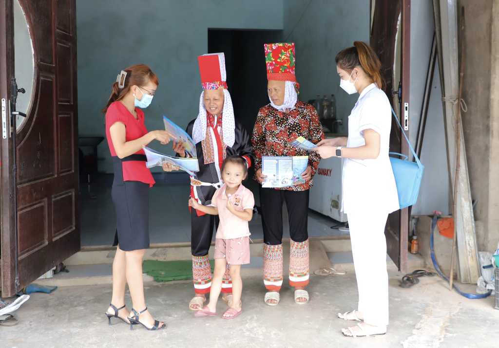 Cán bộ dân số xã Quảng Lâm (huyện Đầm Hà) phát tờ rơi tuyên truyền chính sách DS-KHHGĐ đến với người dân.