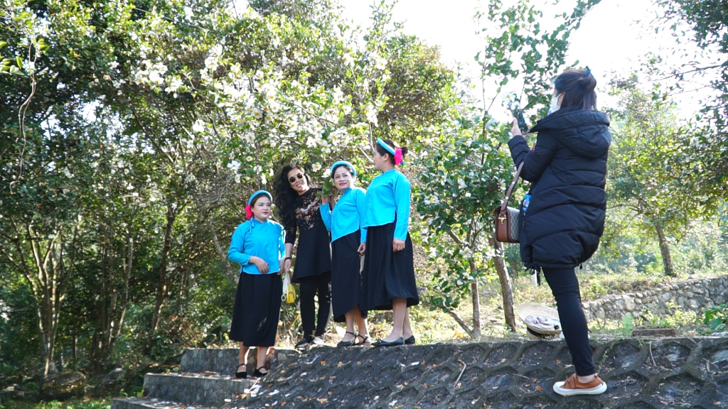 Du khách chụp ảnh lưu niệm cùng người dân địa phương tại rừng sở thôn Đồng Long, xã Đồng Tâm.
