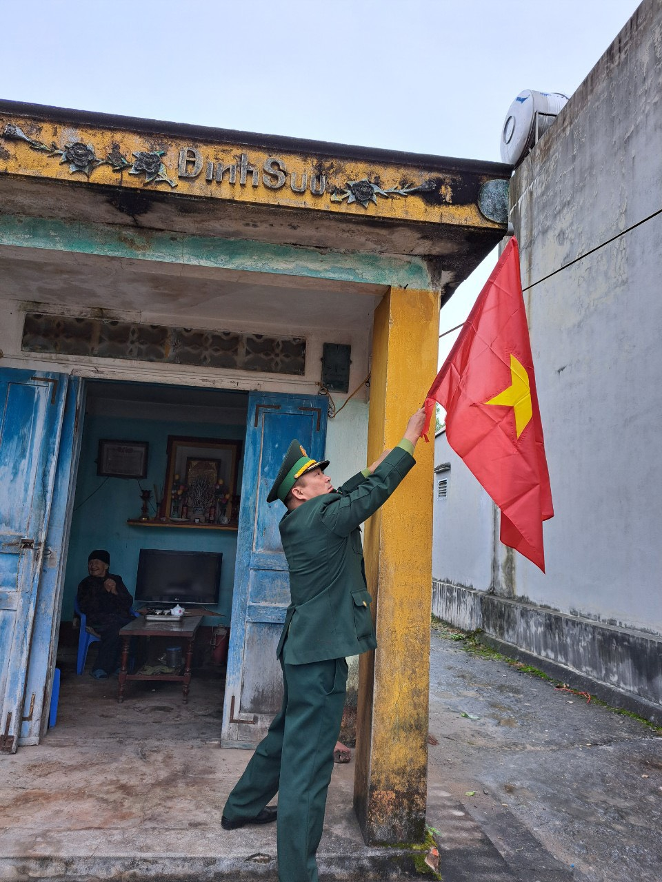 Cán bộ Đồn BP Trà Cổ giúp người già neo đơn treo cờ Tổ quốc đón Tết.