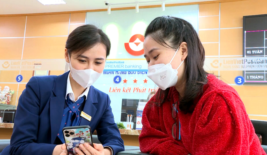 Nhân viên Ngân hàng Thương mại CP Bưu điện Liên Việt hướng dẫn khách hàng cài đặt ứng dụng chuyển tiền từ điện thoại thông minh. Ảnh: Mạnh Trường