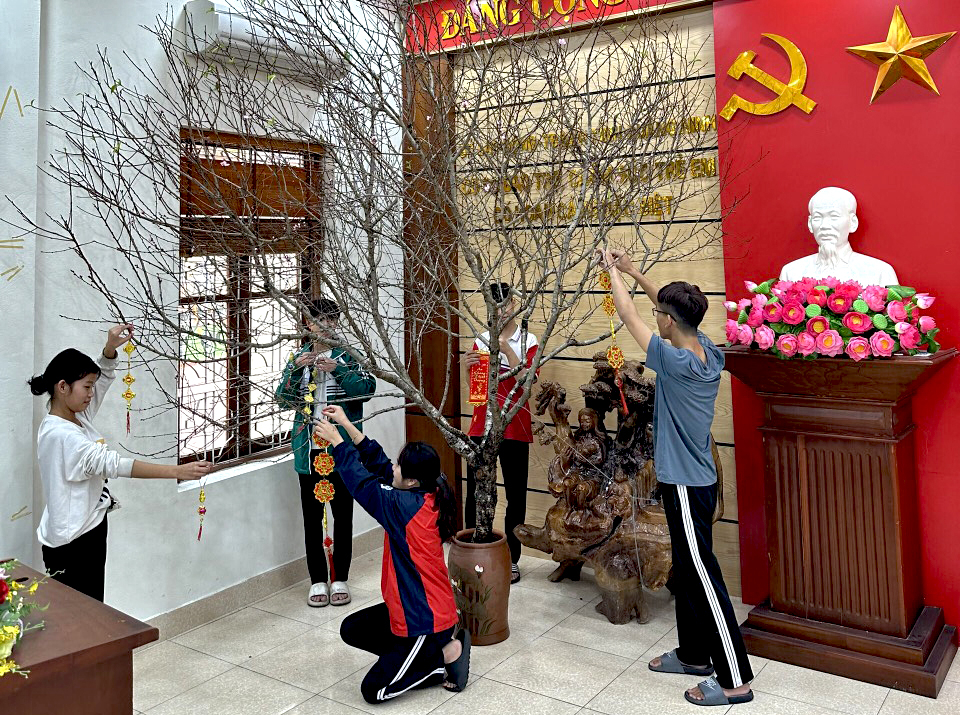 Trẻ em tại cơ sở trang trí cành đào ngày tết.