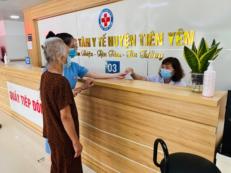 Nhân viên y tế của Trung tâm Y tế huyện Tiên Yên hướng dẫn NCT làm thủ tục khám bệnh.