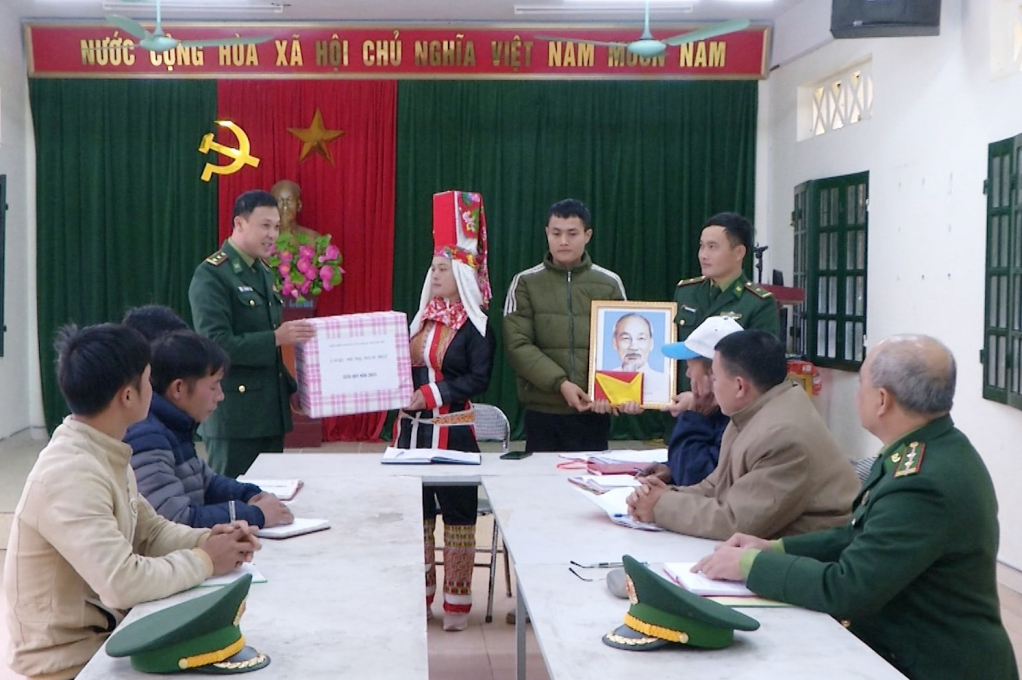 Lãnh đạo Đồn Biên phòng Cửa khẩu Hoành Mô tặng cờ và ảnh Bác Hồ cho người dân thôn Cẩm Hắc, xã Đồng Văn (huyện Bình Liêu).
