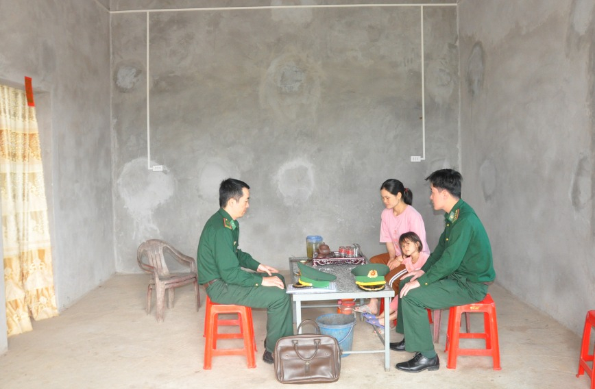 Cán bộ chiến sỹ Đồn BP Quảng Đức trò chuyện với chị Phò ong Nhì Múi, bản Nà Lý, xã Quảng Đức trong căn nhà 