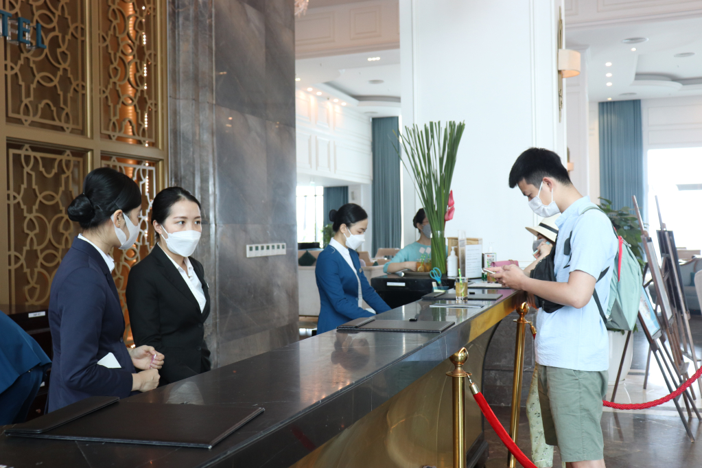 Nhân viên tại quầy lễ tân khách sạn FLC đeo khẩu trang để hướng dẫn cung cấp dịch vụ, đảm bảo an toàn cho du khách. 