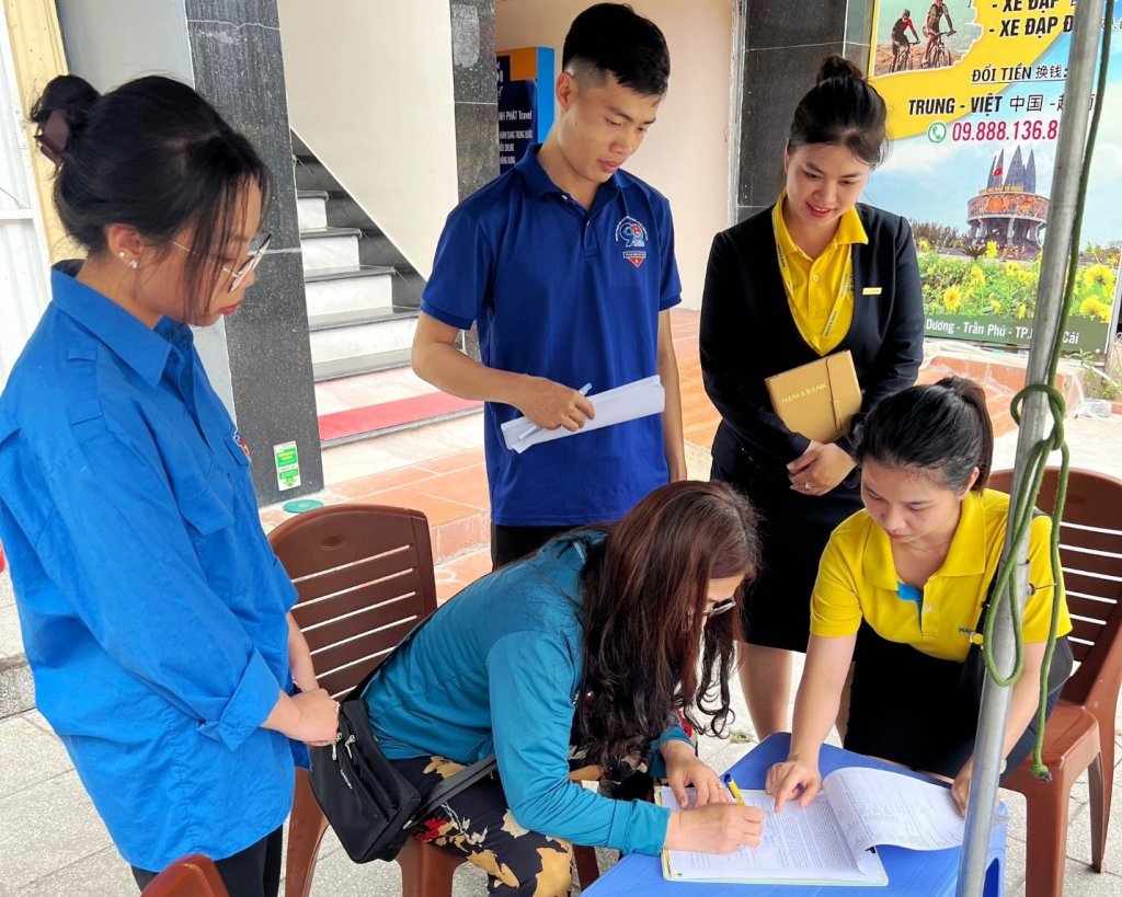 Đoàn thanh niên thành đoàn Móng Cái cùng với nhân viên ngân hàng Nam Á bank mở tài khoản thanh toán không dùng tiền mặt cho người dân.