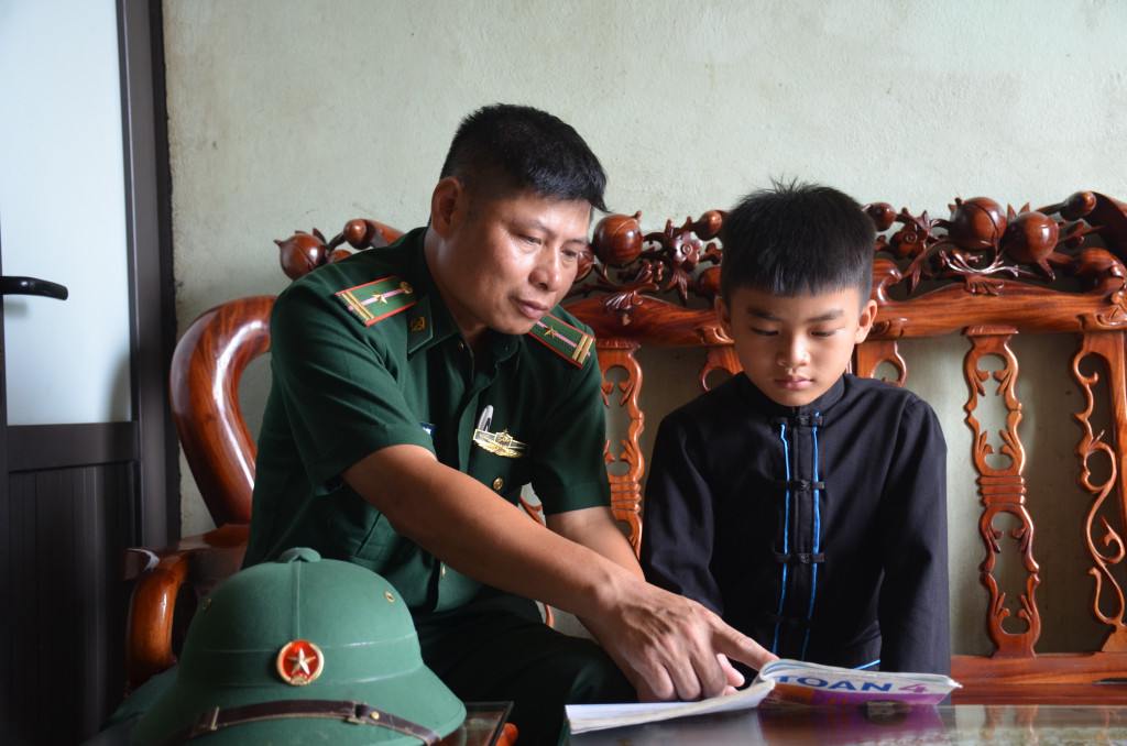 Thiếu tá Bùi Văn Đông, cán bộ Đồn BPCK Hoành Mô đến nhà kèm cháu Trần Tiến Hưng học bài.