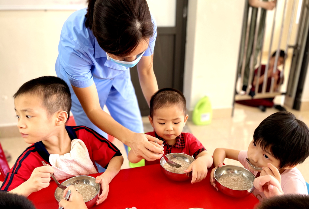 Bữa cháo sáng với đầy đủ chất dinh dưỡng. Các em nhỏ được bón cho từng thìa cháo.