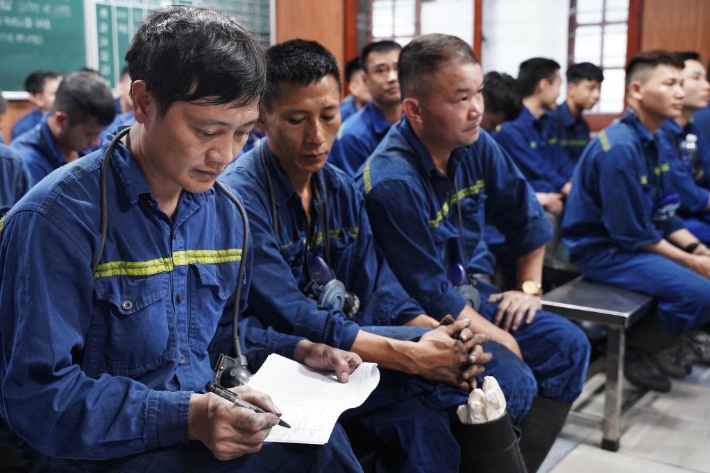 Ca 1 của nhóm thợ lò Bùi Tất Tuyên kéo dài 8 tiếng. Mỗi tuần anh phải đảo ca liên tục. Suốt 8 tiếng làm việc dưới lò sâu nhiệm vụ đặc biệt của anh và đồng đội là phải đảm bảo an toàn tuyệt đối. Ảnh chụp thợ lò Bùi Tất Tuyên ký sổ an toàn trong giờ giao ca.
