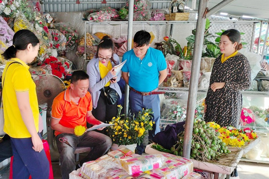 Cán bộ BHXH huyện Hải Hà và Bưu điện huyện Hải Hà tuyên truyền về chế độ chính sách cho hộ tiểu thương tại thị trấn Quảng Hà.