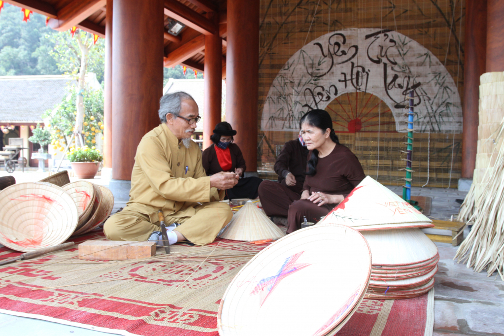 Nghệ nhân dân gian Phạm Thanh Lương hướng dẫn du khách làm nón lá truyền thống tại khu nghỉ dưỡng Làng Nương, Yên Tử.