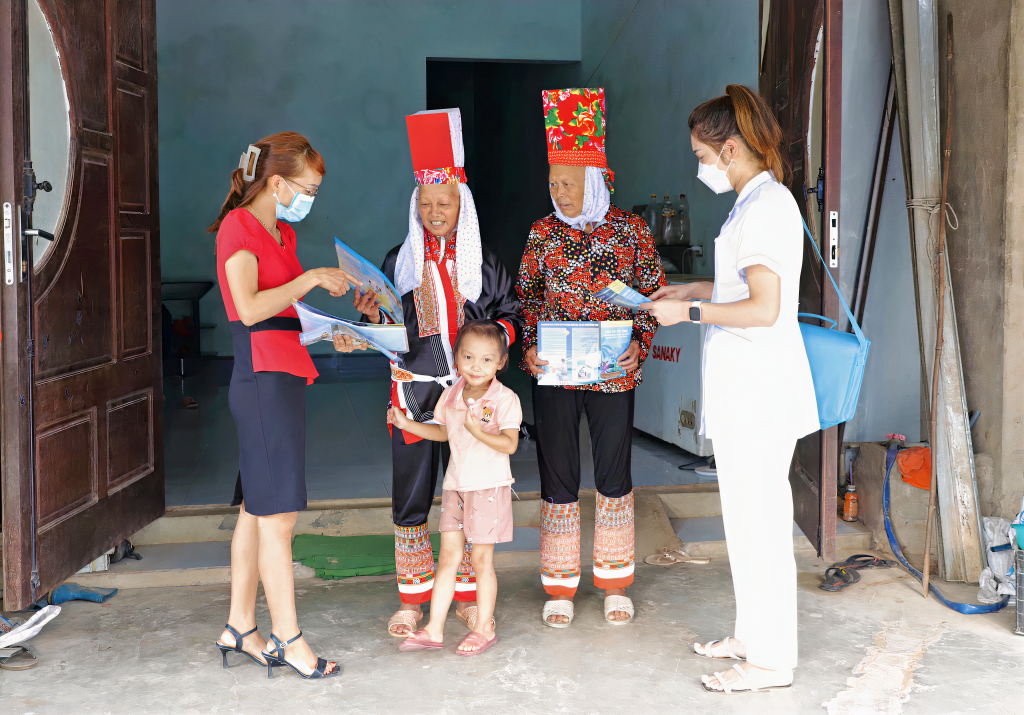 Cán bộ dân số xã Quảng Lâm (huyện Đầm Hà) phát tờ rơi tuyên truyền chính sách DS-KHHGĐ đến người dân.