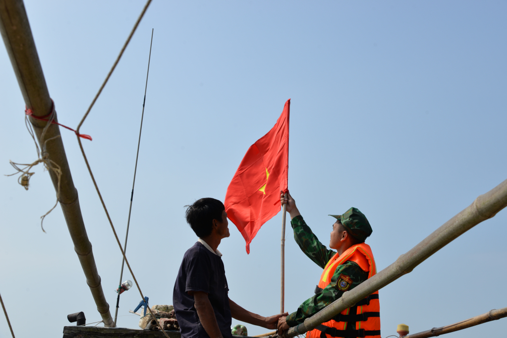 Cán bộ Đồn BPCK Cảng Vạn Gia giúp ngư dân treo cờ Tổ quốc.
