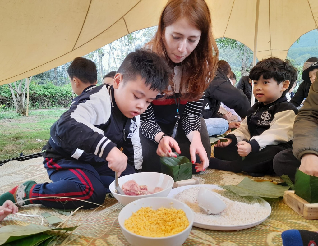Các em nhỏ trải nghiệm gói bánh chưng trong hoạt động ngoại khóa tại Thiên đường hoa Quảng La. 